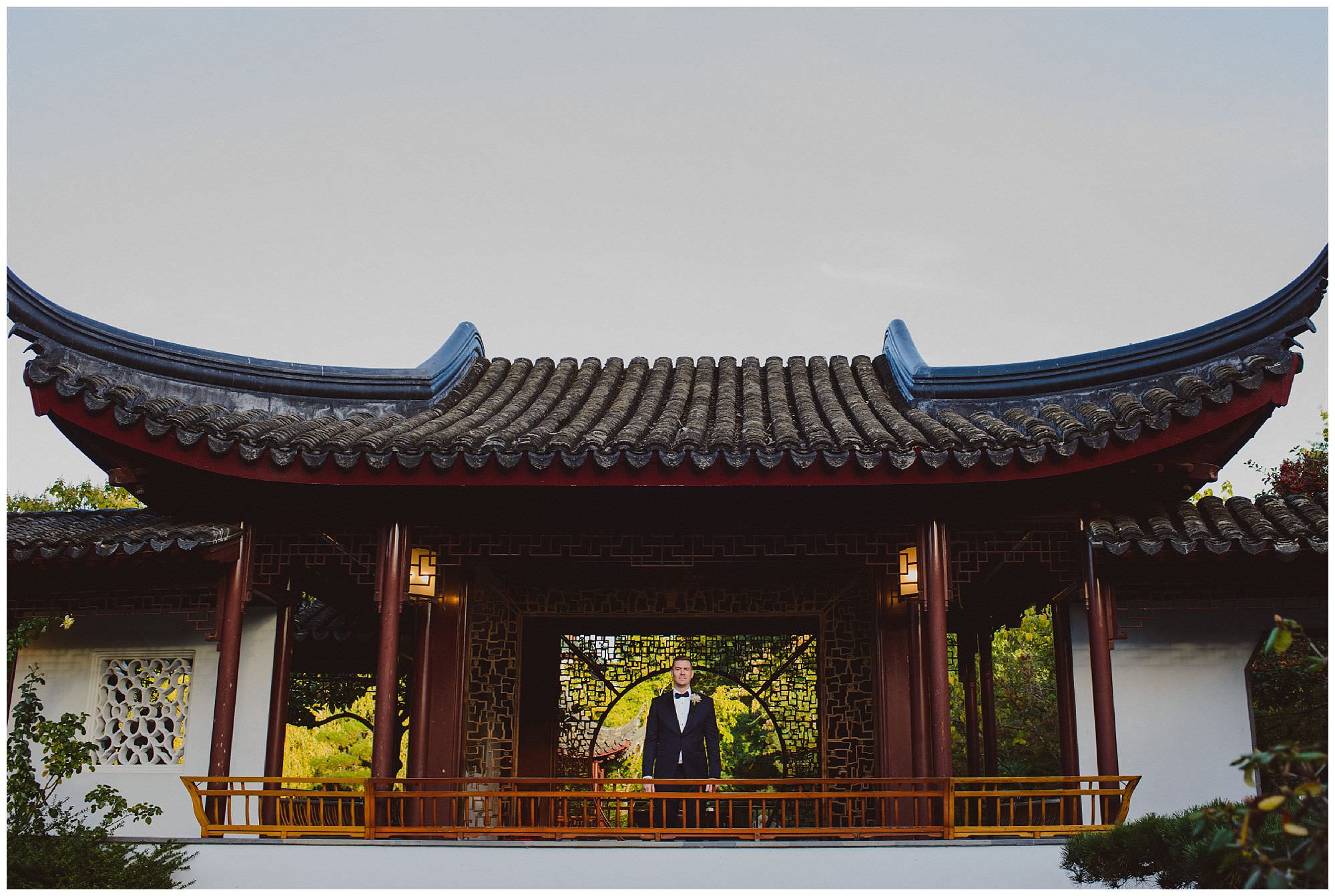 Groom in classic black tie suit stands in Dr. Sun Yat-Sen Classical Chinese Gardens after his intimate wedding, Vancouver wedding photographer